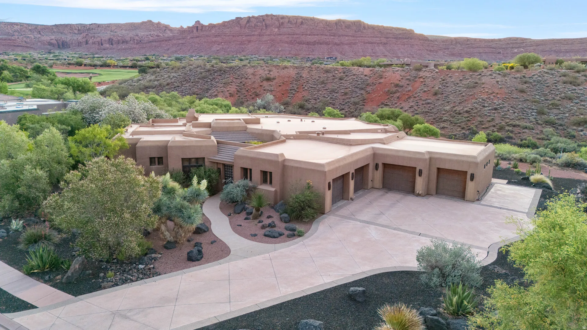 Southwestern-style residence featuring a stucco exterior, integrated three-car garage, and a curved concrete driveway