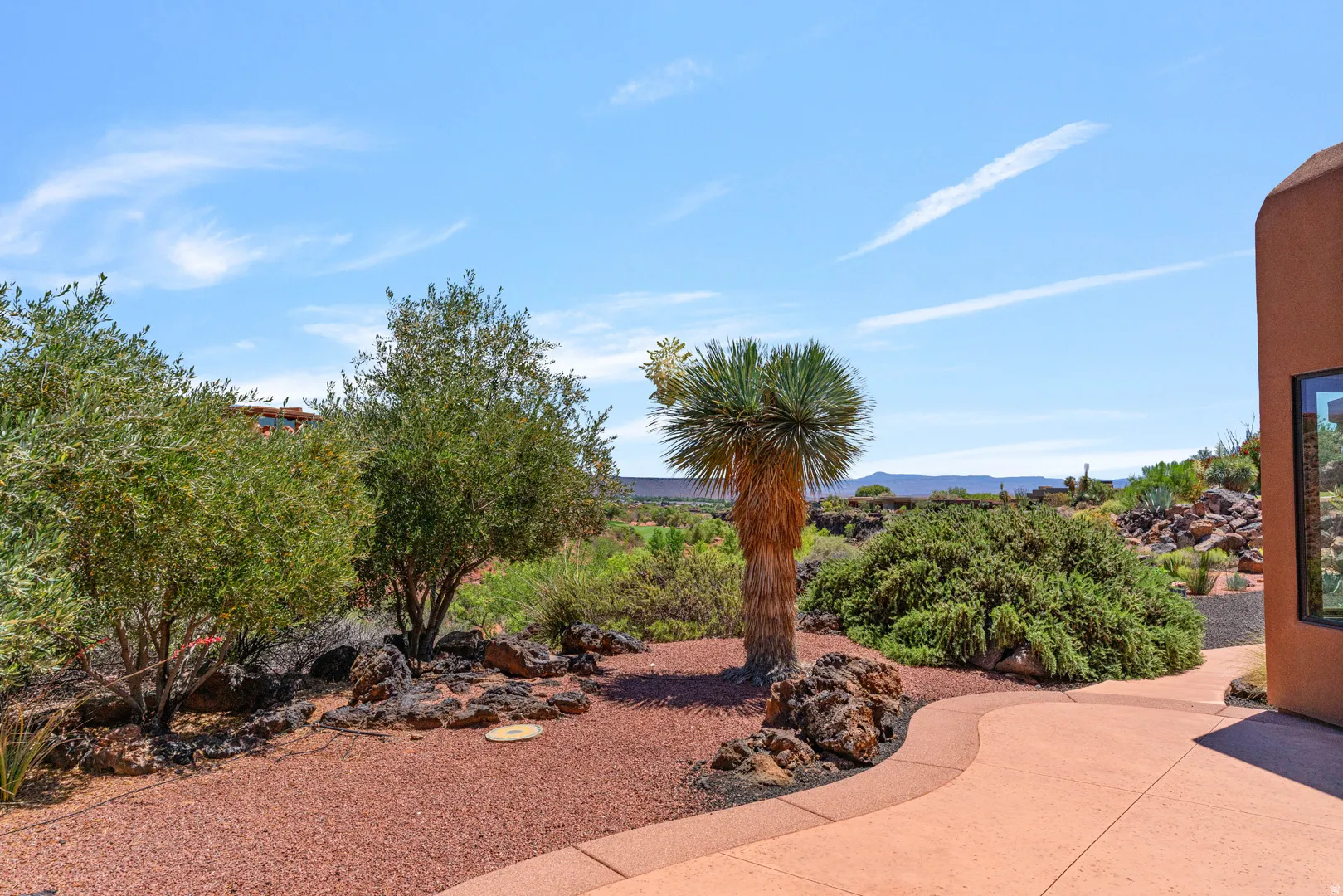 Desert-landscaped exterior featuring a yucca plant and mature shrubs