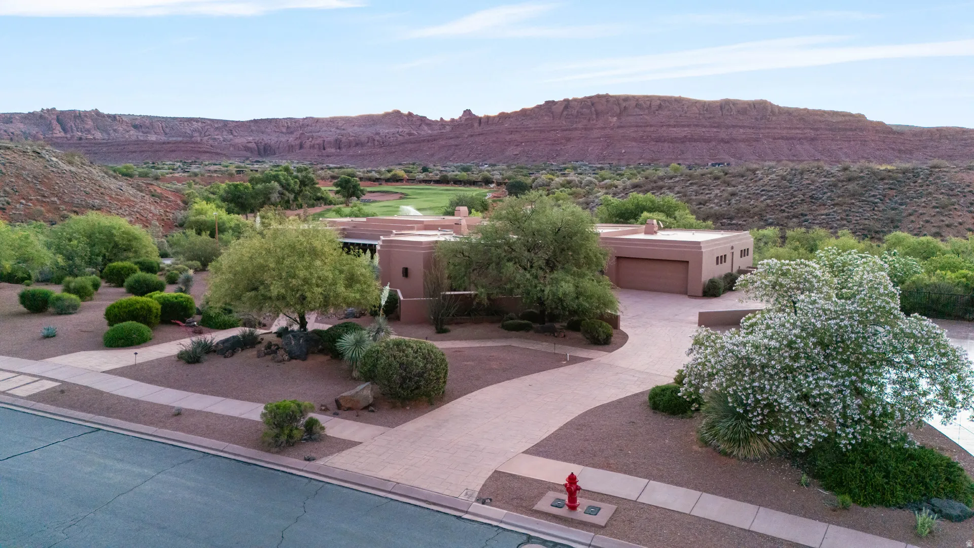 Desert contemporary residence featuring a two-car garage, mature landscaping, and a curvilinear driveway