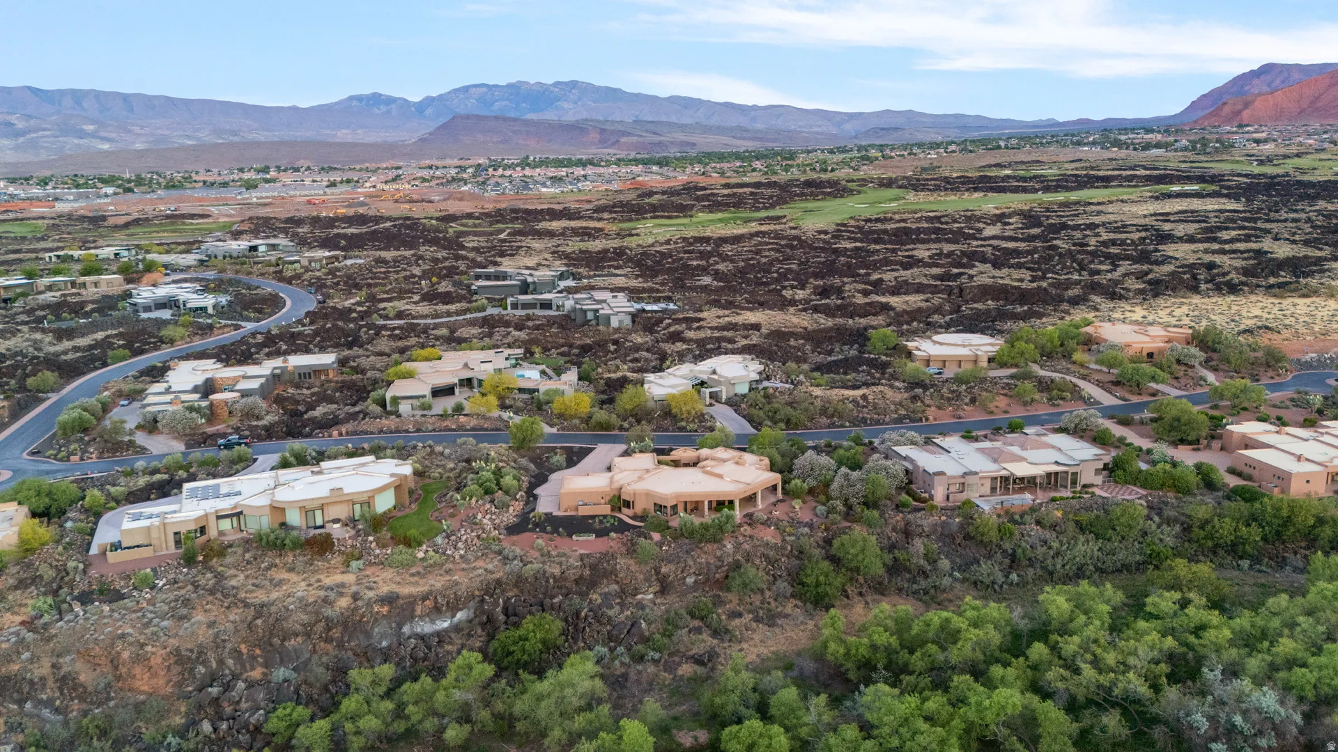 Desert landscape featuring multiple contemporary residences, winding roadways, and distant red rock formations