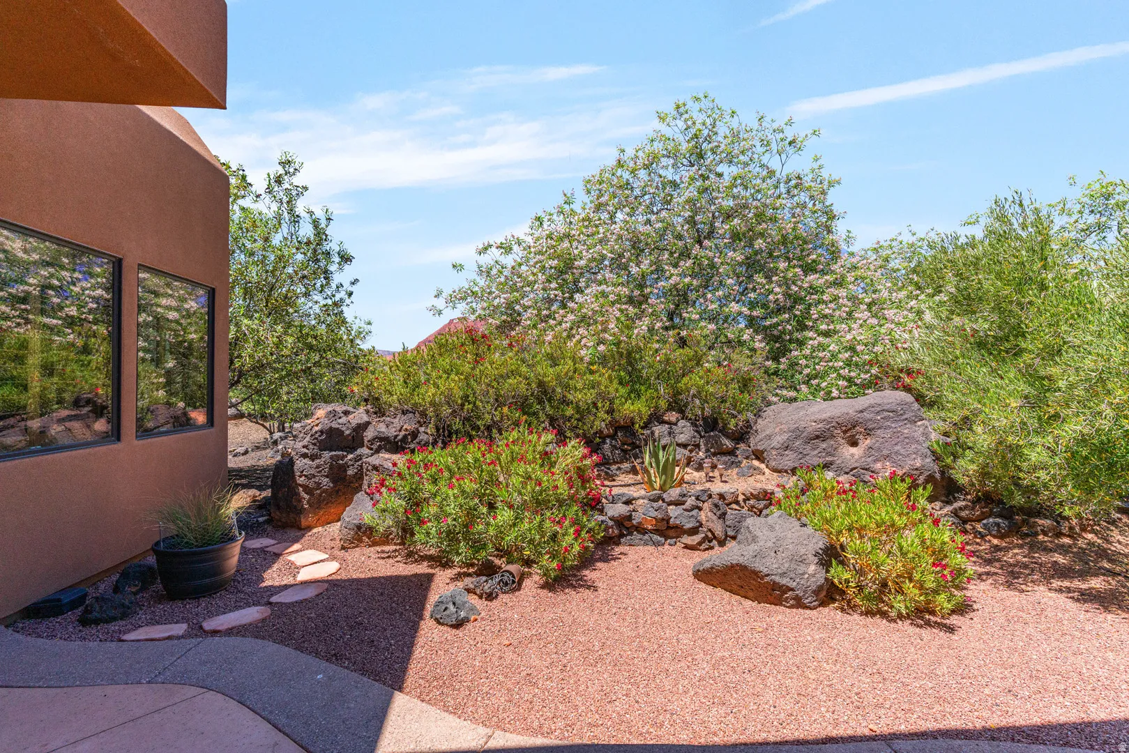Southwestern-style landscaping featuring red gravel, large natural boulders, and established shrubs