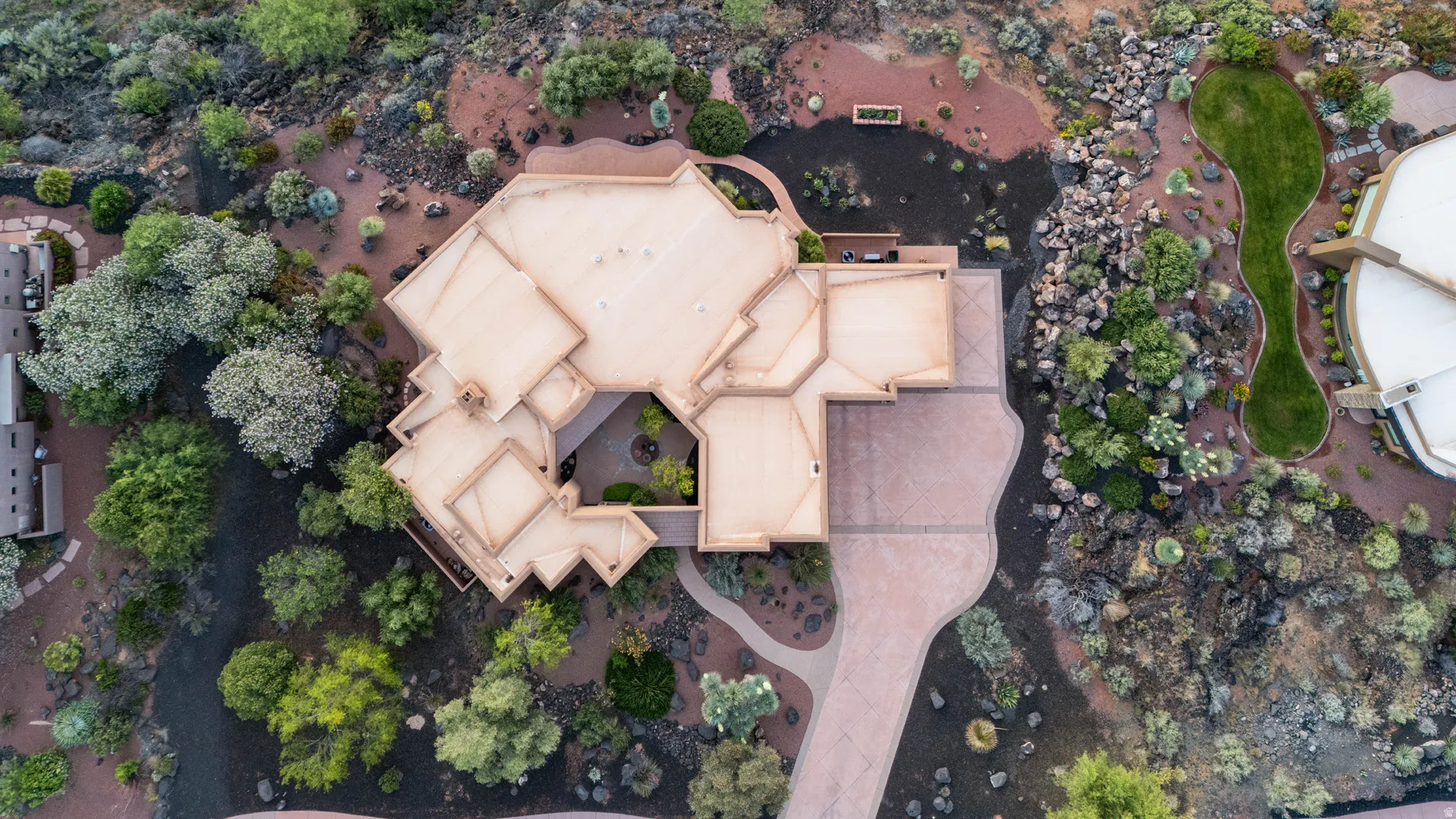 Expansive property featuring a multi-level roofline, a central courtyard, and a curving paved driveway