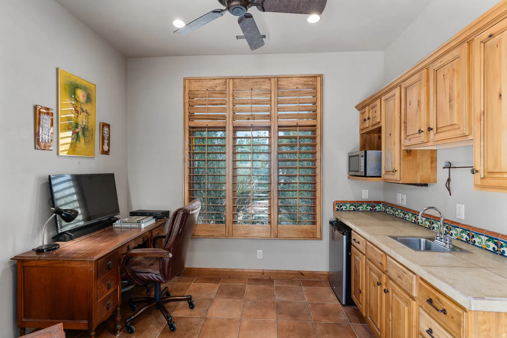 Wet bar featuring a stainless steel sink, under-counter refrigerator, built-in microwave, and wood-finish cabinetry