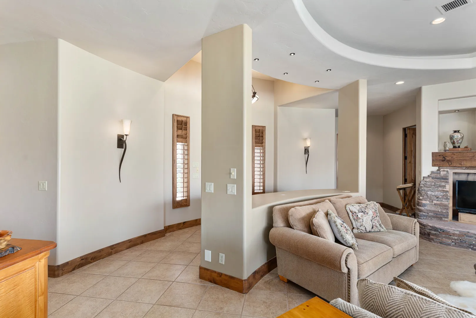 Living space featuring a stone-clad fireplace, a wood mantel, and an arched ceiling with recessed lighting