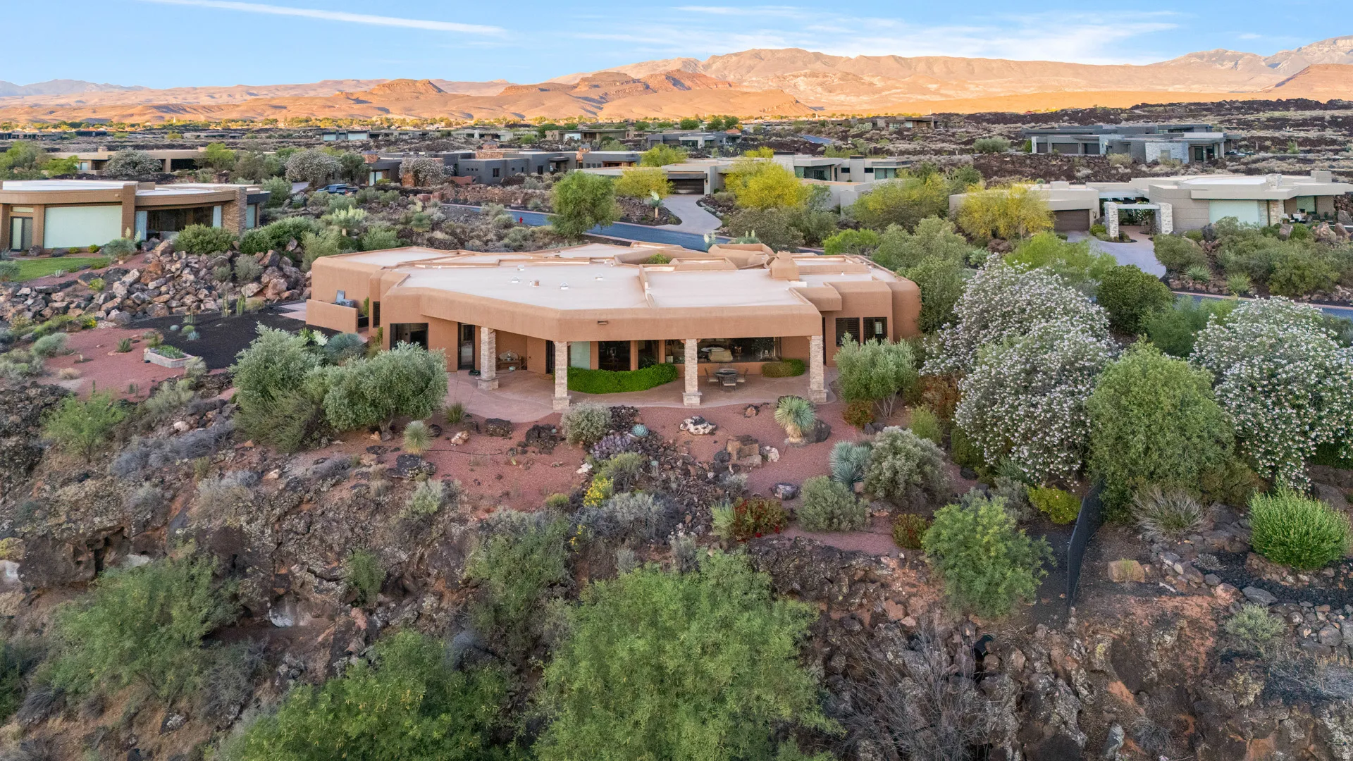 Desert contemporary architecture featuring an expansive patio, covered outdoor living space, and mature drought-tolerant landscaping