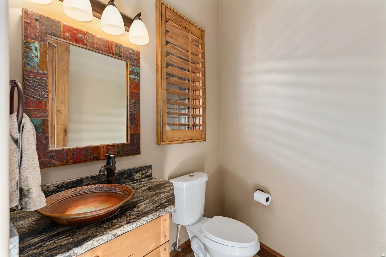 Powder room featuring a unique vessel sink, patterned countertop, and a decorative framed mirror