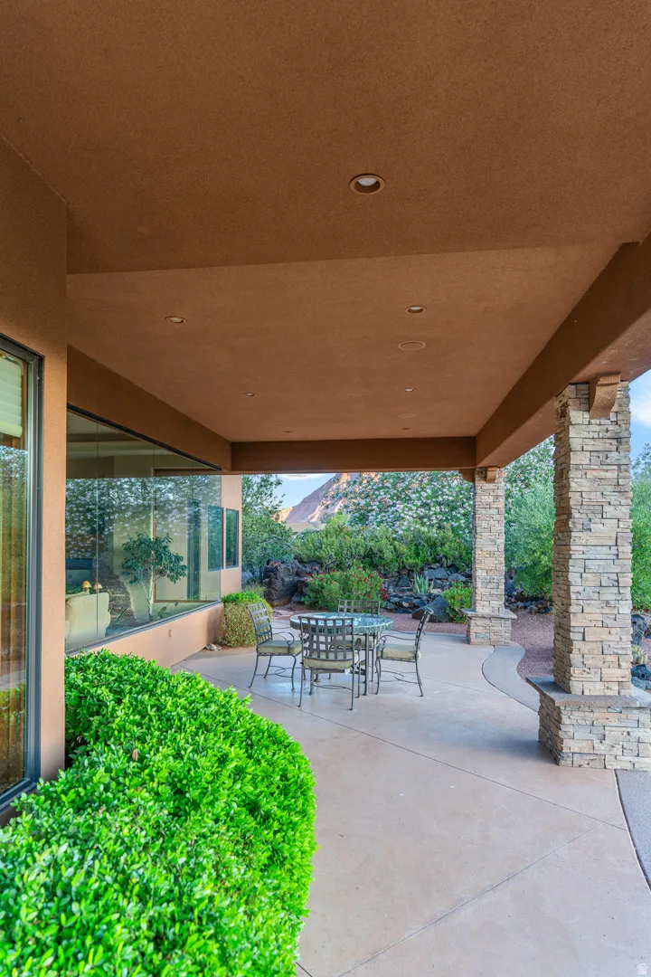 Covered patio featuring recessed lighting, a smooth concrete surface, and stacked stone columns