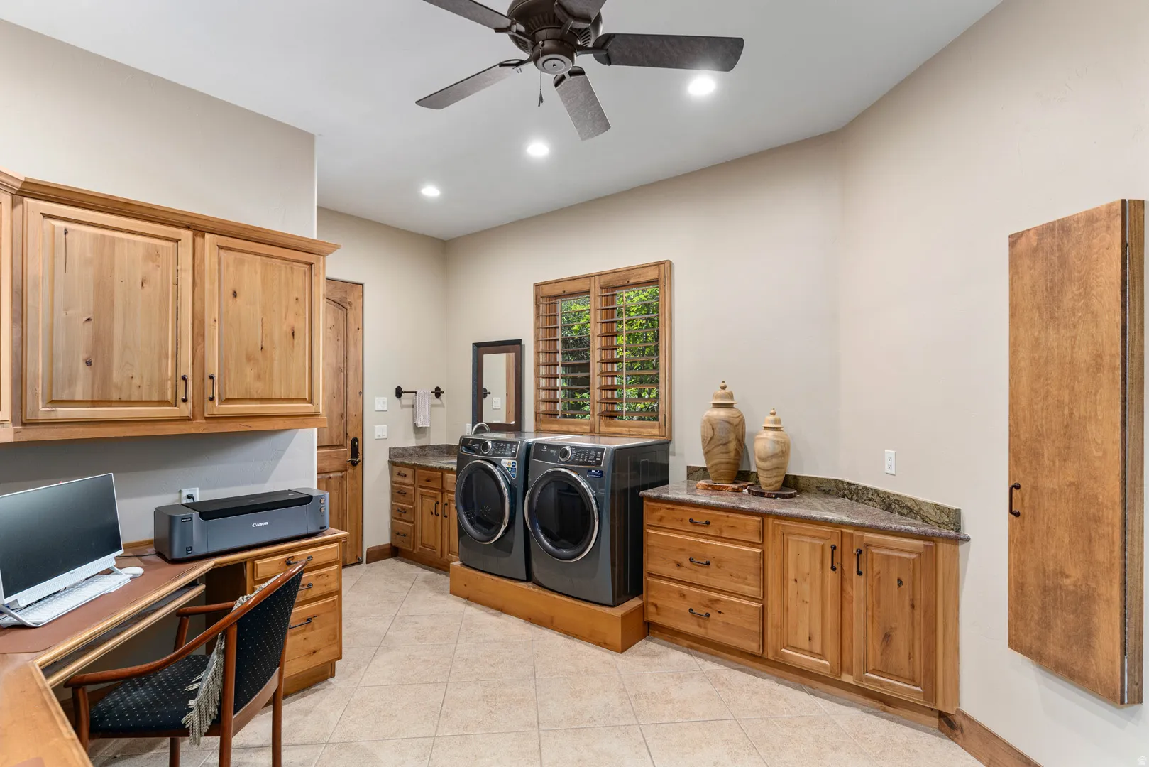 Functional laundry room featuring tile flooring, wood cabinetry with stone countertops, a ceiling fan, and recessed lighting