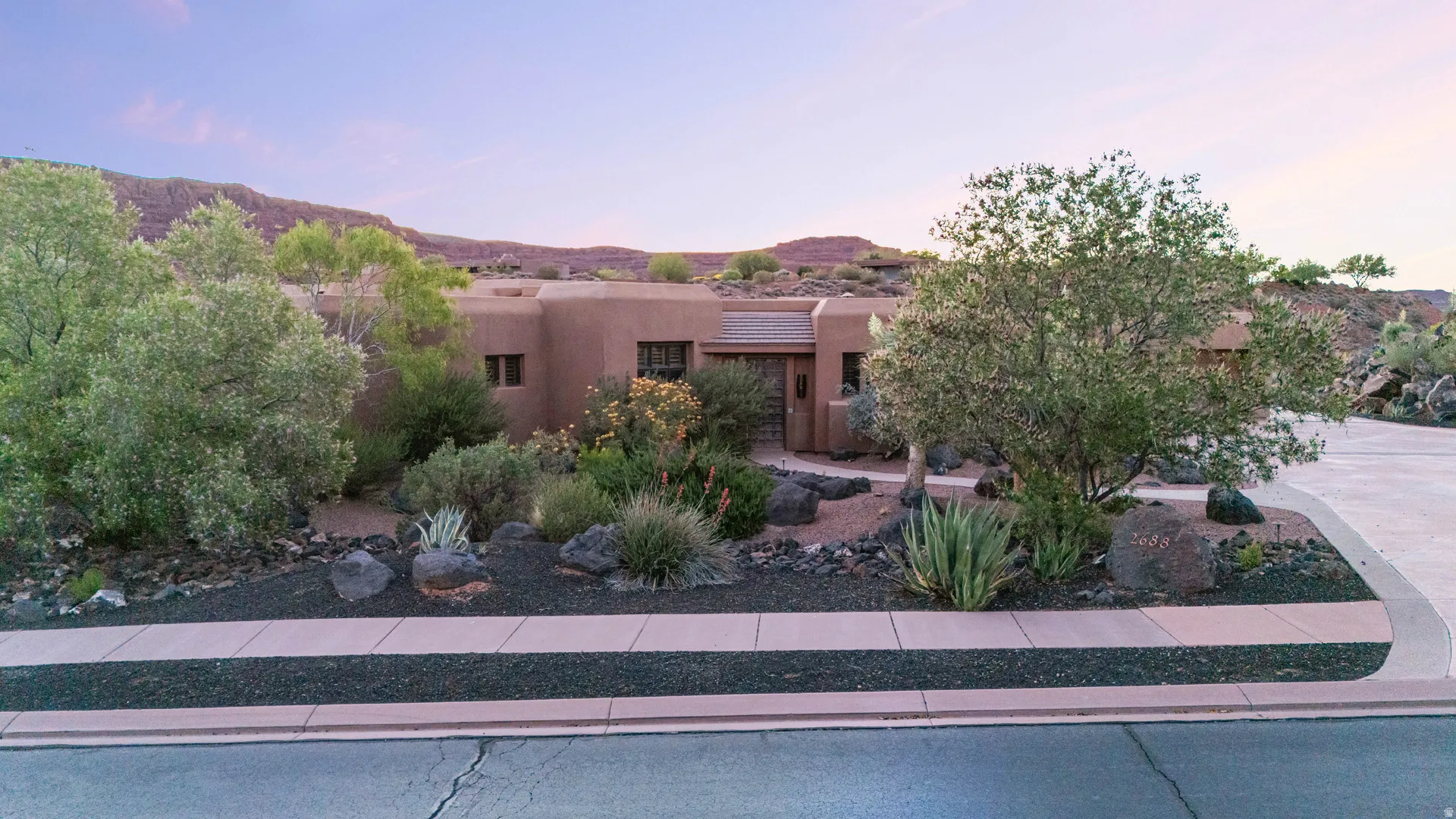 Adobe-style exterior with a flat roofline, featuring a desert-adapted landscape design