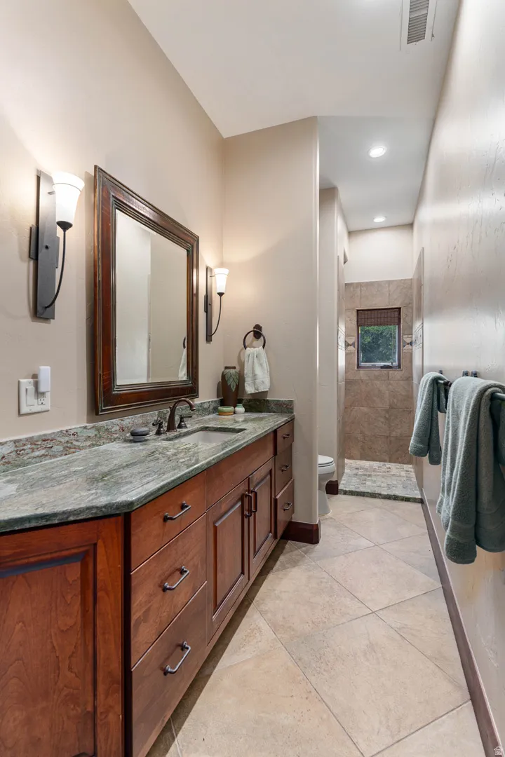 Expansive vanity featuring wood cabinetry, a stone countertop, and an undermount sink