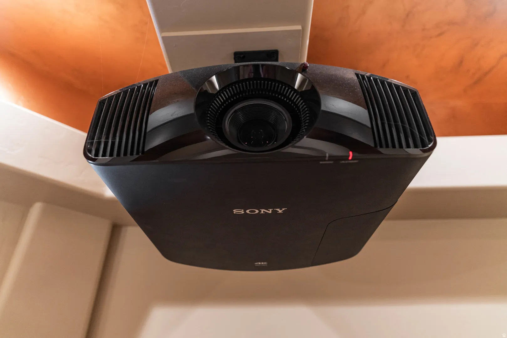 Ceiling-mounted projector with visible lens and ventilation grilles