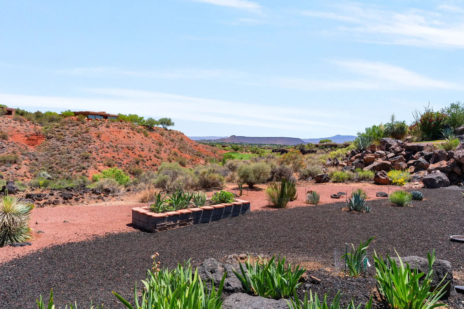 Desert landscape featuring black lava rock and red gravel ground cover