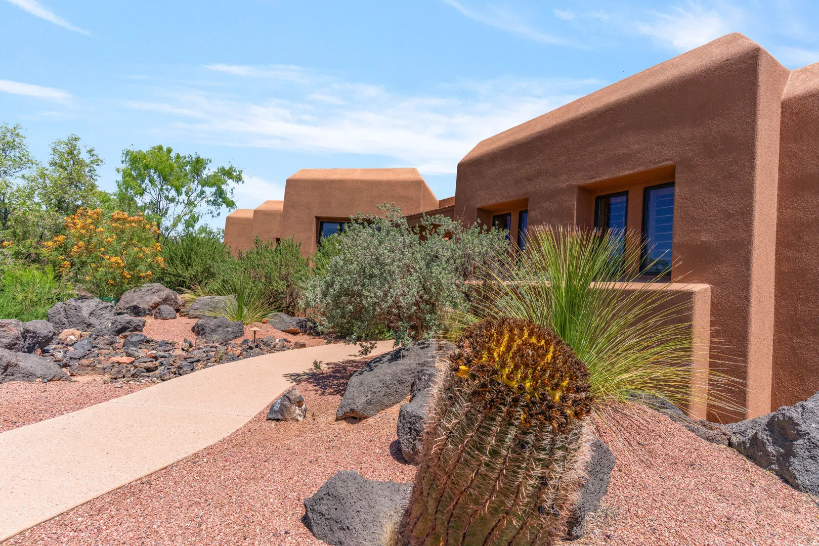 Southwestern-style architecture featuring a textured stucco exterior, dark-framed windows, and a flat roofline