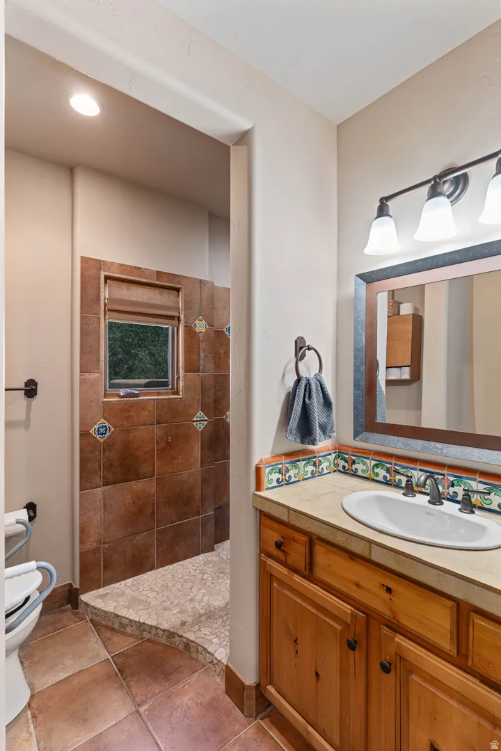 Guest suite bathroom featuring a wood vanity with a drop-in sink, an overhead three-light fixture, and a framed mirror