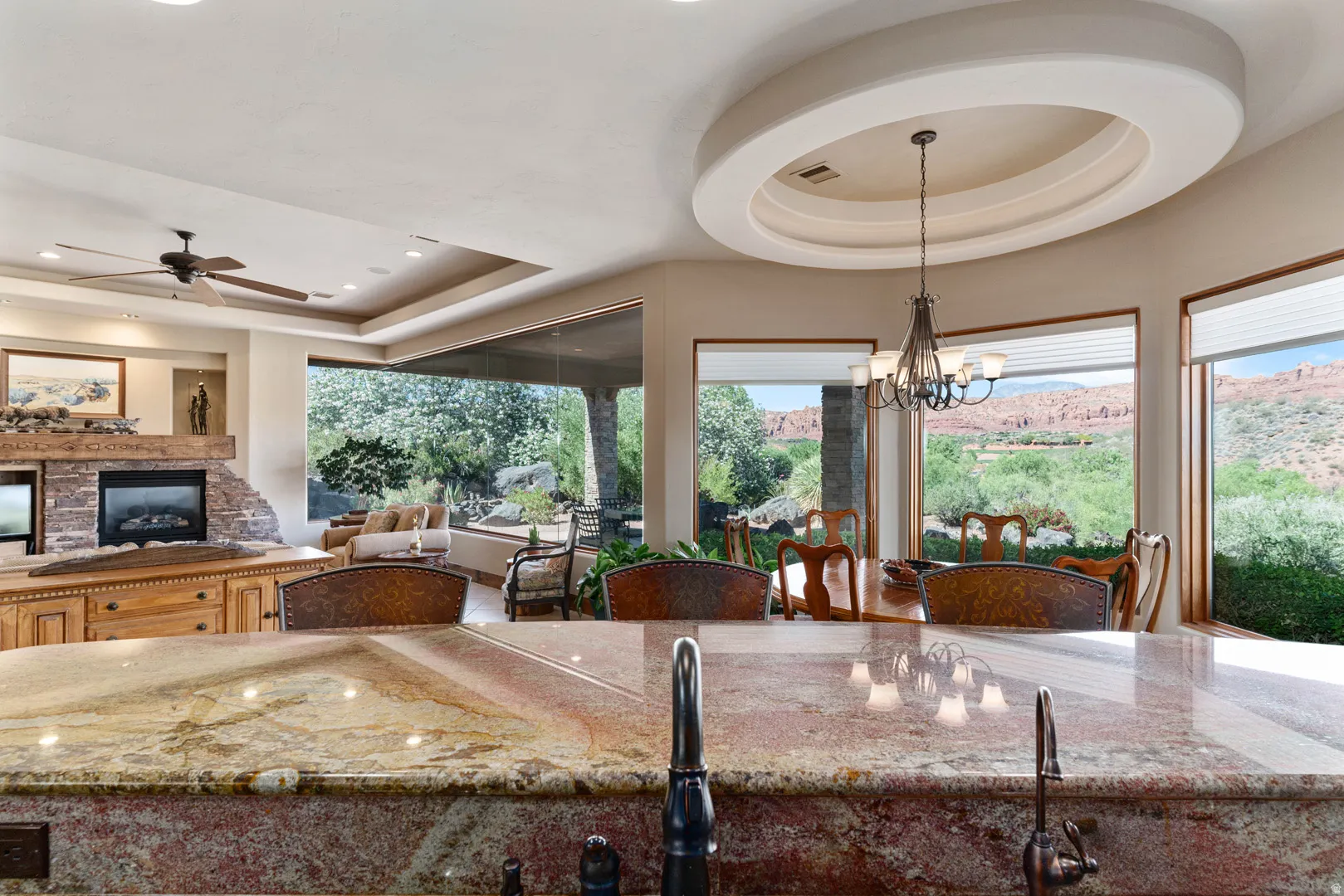 Spacious open-concept interior featuring a stone-clad fireplace with a wood mantle, a built-in entertainment console, and a ceiling fan