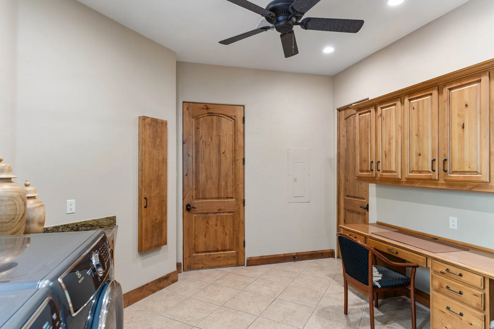 Laundry room with wood-finish cabinetry, built-in desk, and ceiling fan