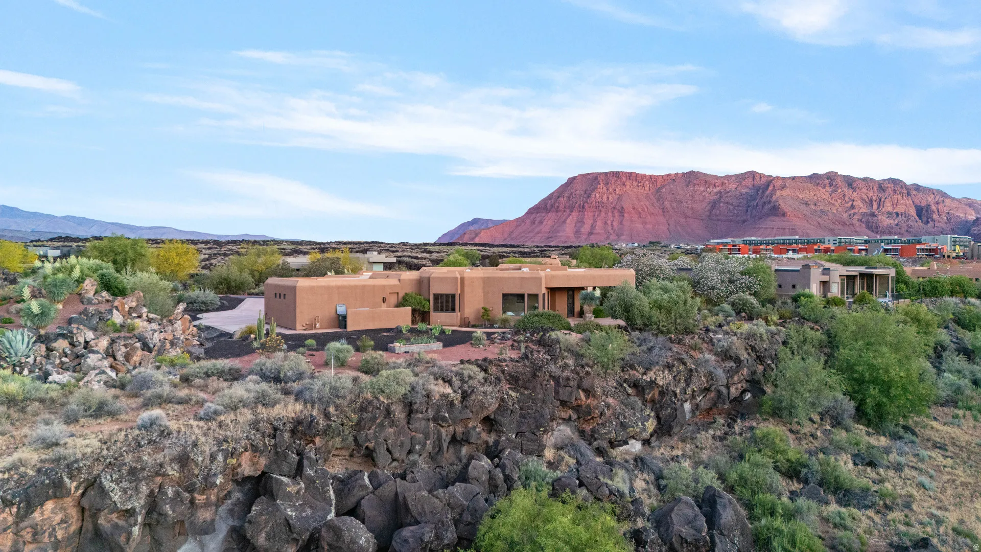 Southwestern-style residence featuring a flat roofline and stucco exterior, set against a backdrop of red rock mountains