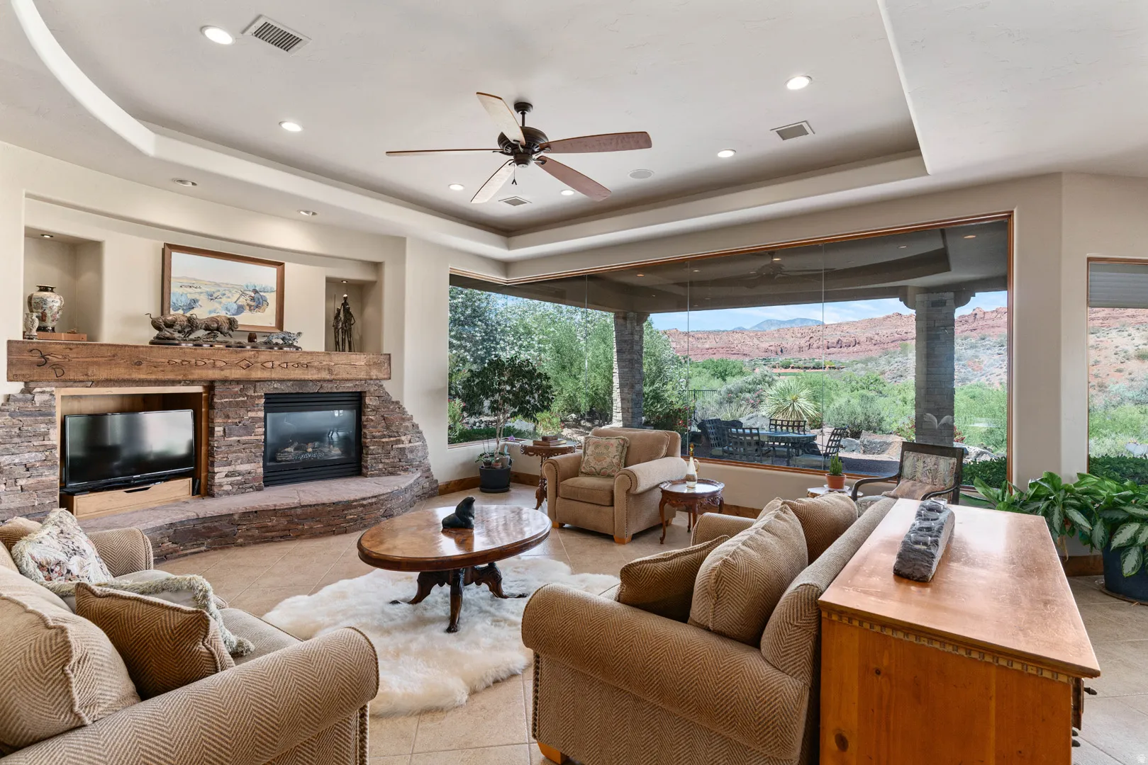 Expansive living area featuring a stone-clad fireplace with a substantial wood mantel, a built-in media niche, and tray ceilings with recessed lighting