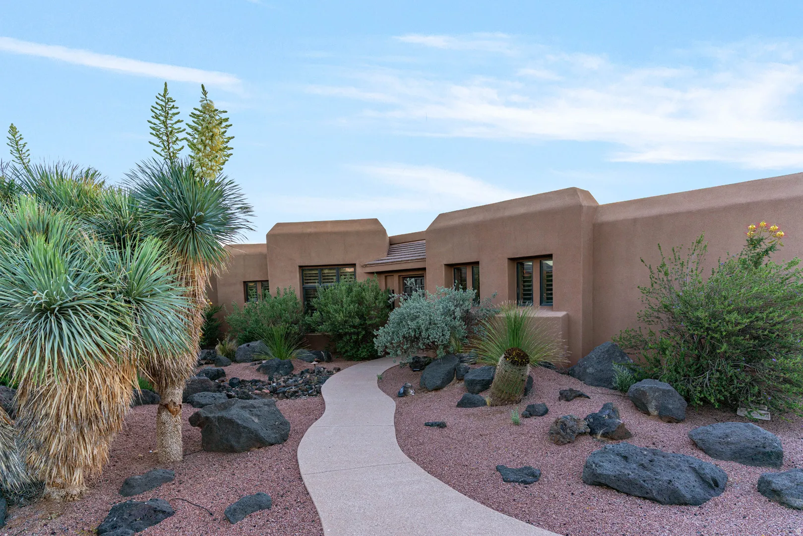 Southwestern-style architecture featuring a stucco exterior and multiple windows with louvered shutters