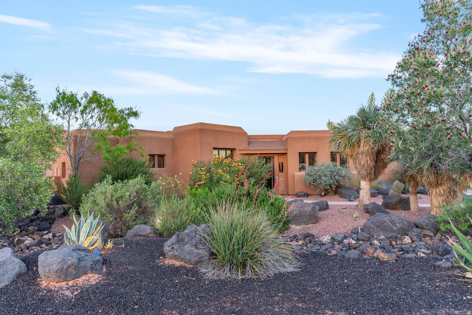 Southwest-style exterior featuring a muted orange facade, multiple windows with dark frames, and a prominent front entrance