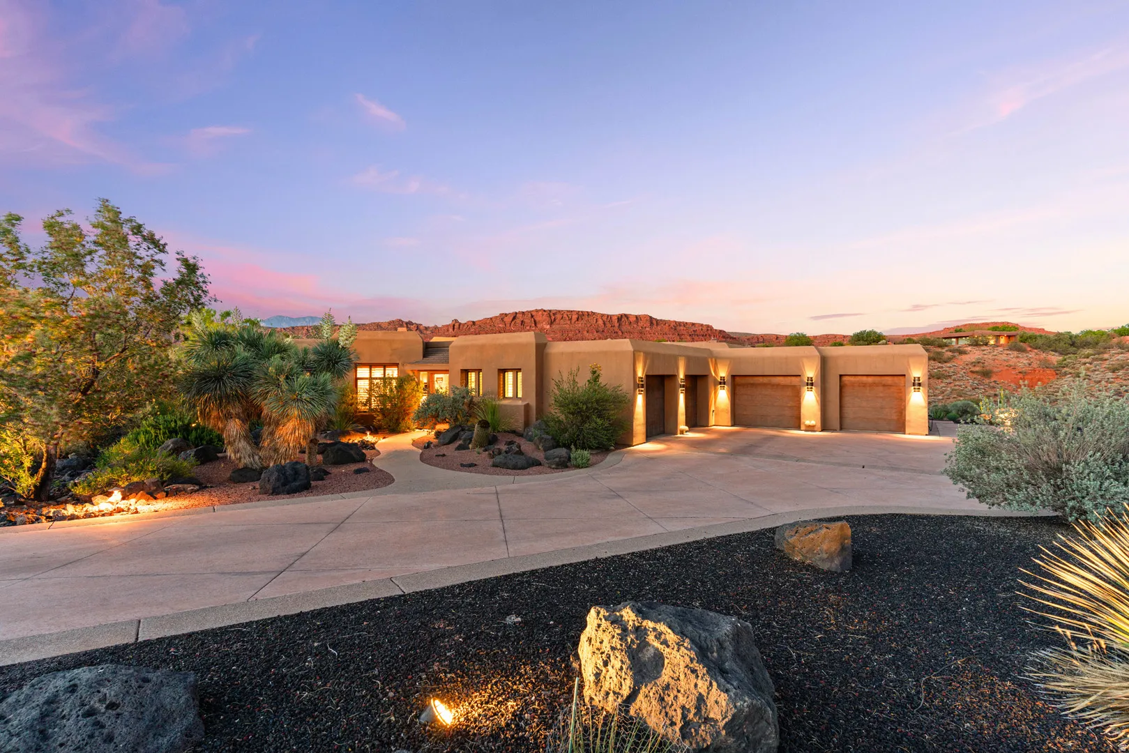 Southwestern-style residence featuring a stucco exterior, a curved concrete driveway, and three garage bays with wood-finish doors