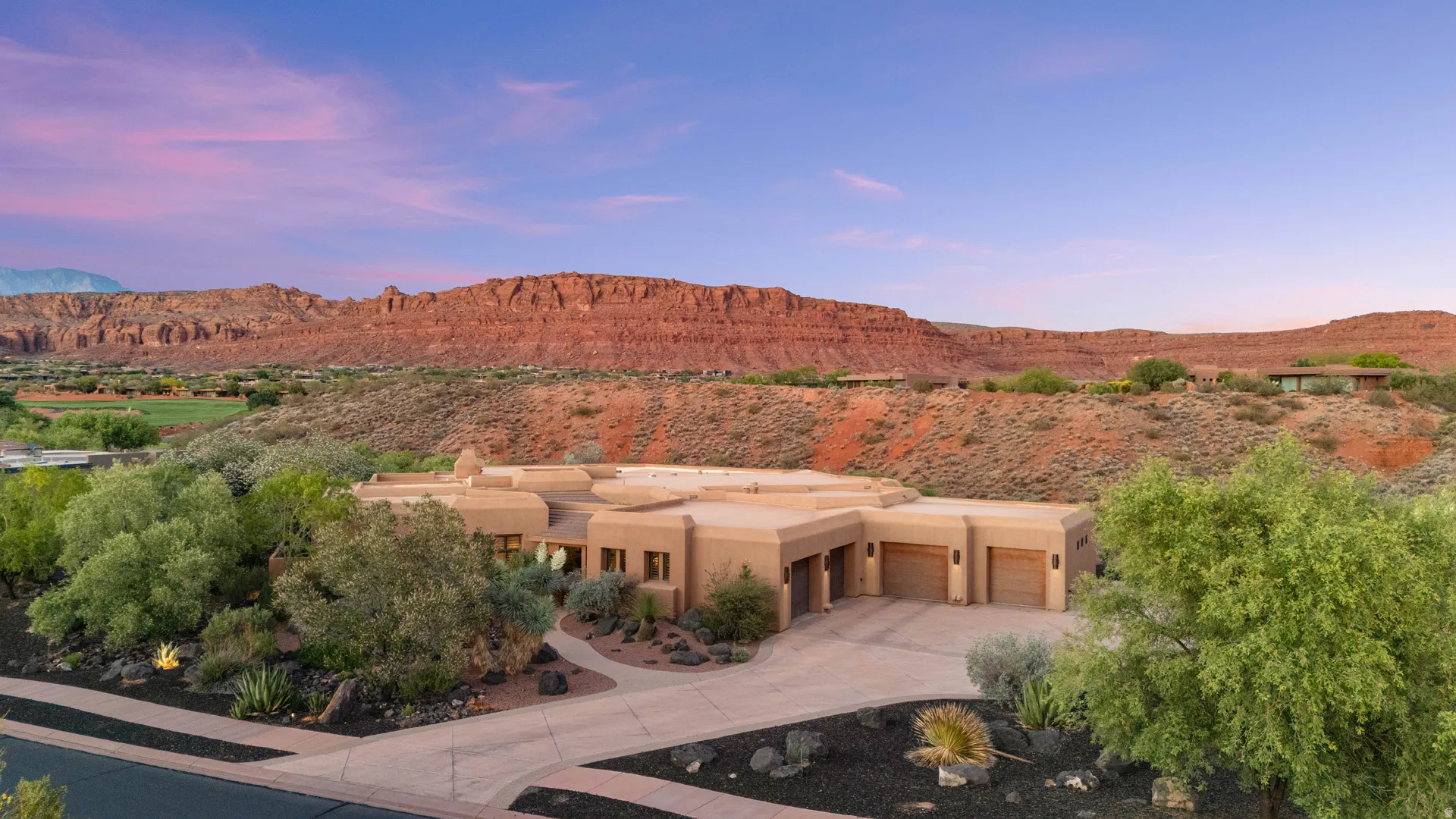 Desert modern residence with a stucco exterior, integrated three-car garage, and expansive paved driveway