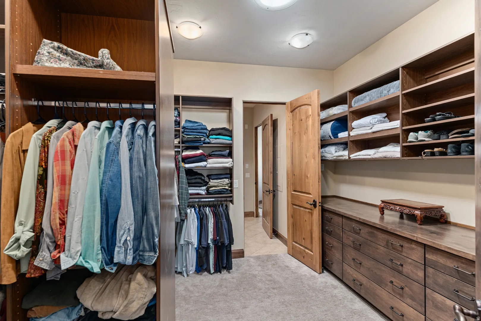 Primary custom closet system featuring wood-finish cabinetry, integrated shelving, ample hanging space, and built-in drawers