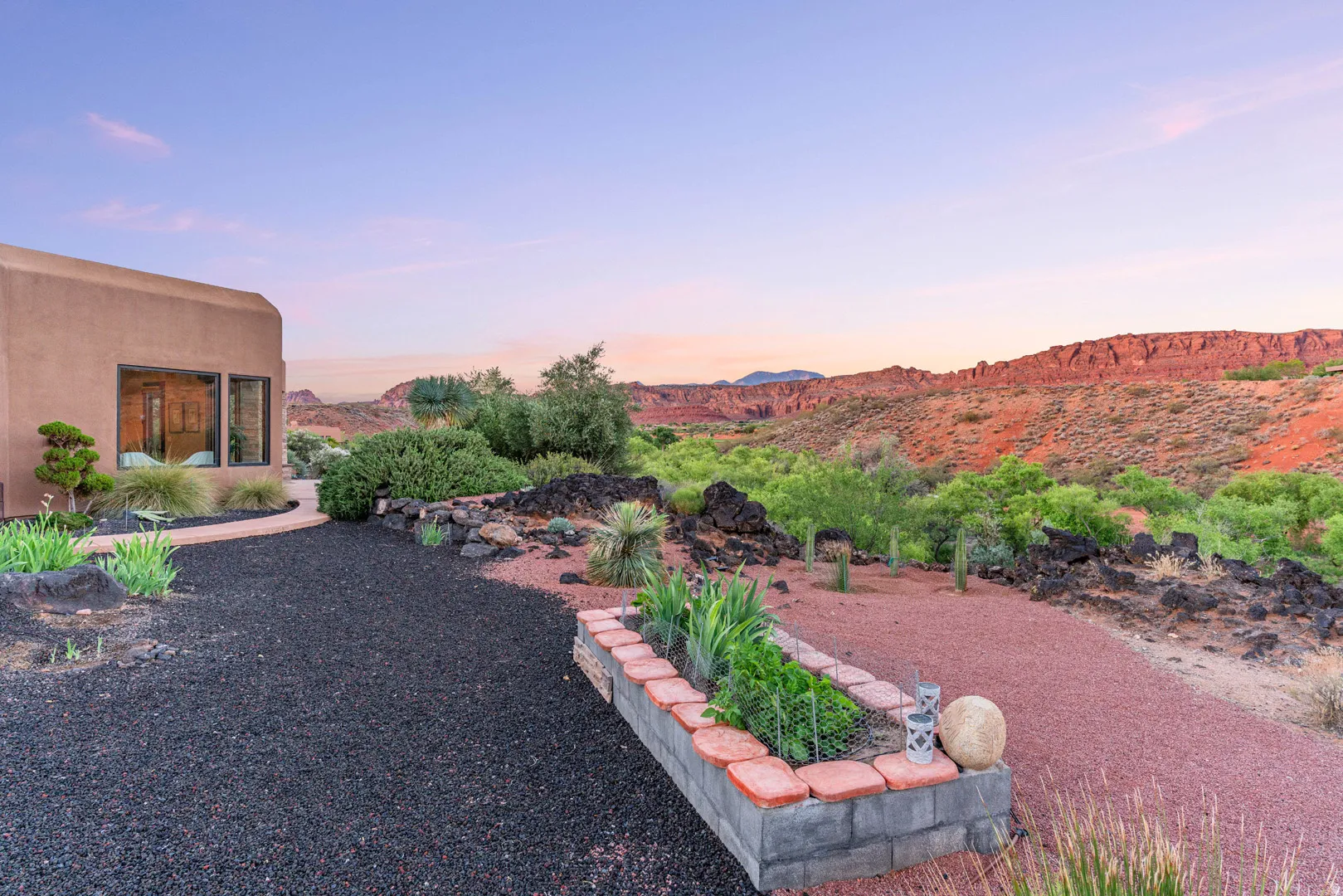 Desert landscape property featuring a stucco exterior, gravel pathways, and a raised garden bed with brick coping