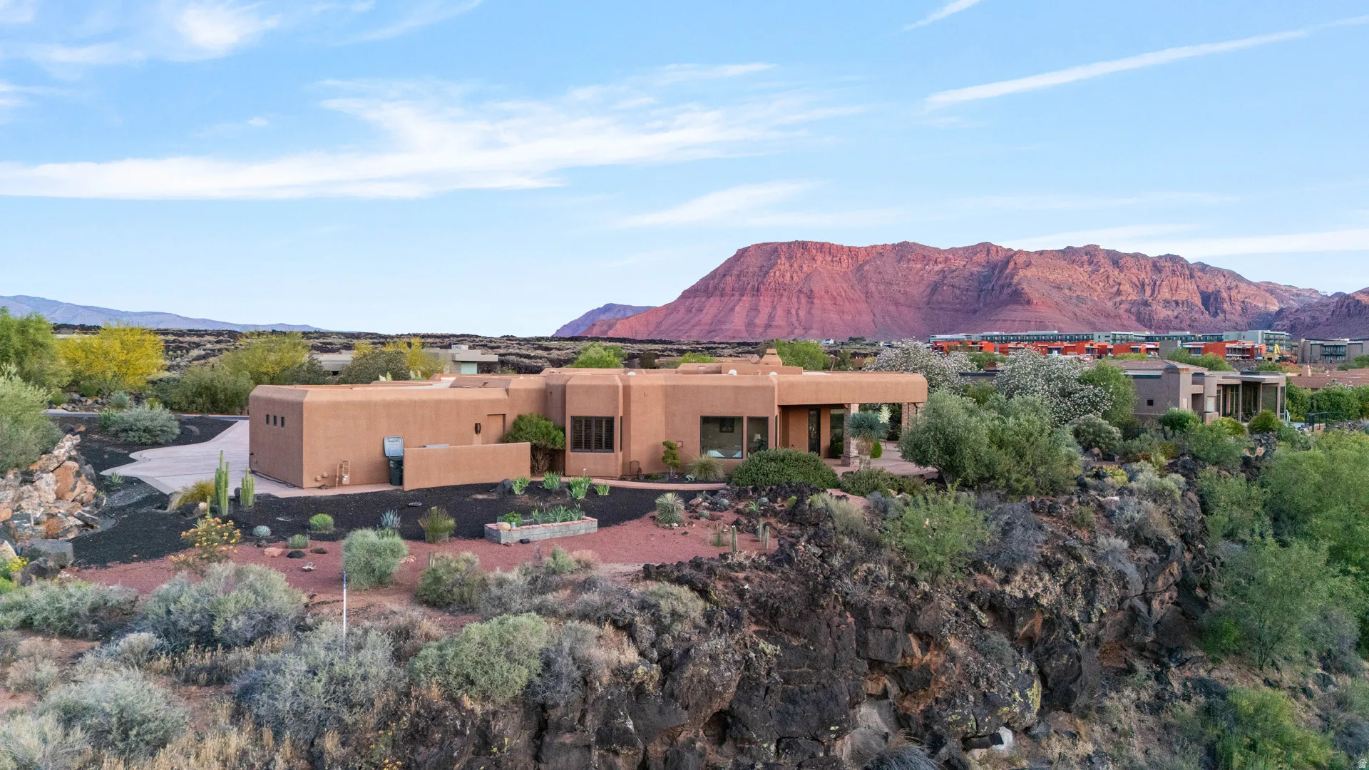 Adobe-style architecture with a stucco exterior, integrated flat roofline, and desert landscaping