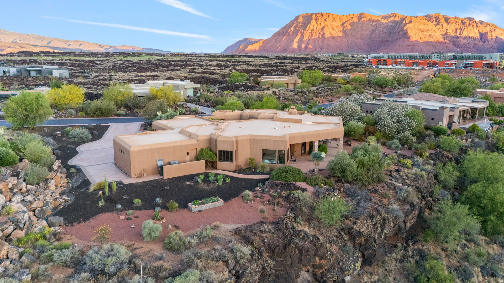 Southwestern-style residence featuring stucco exterior, a private driveway, and a natural rock landscaping