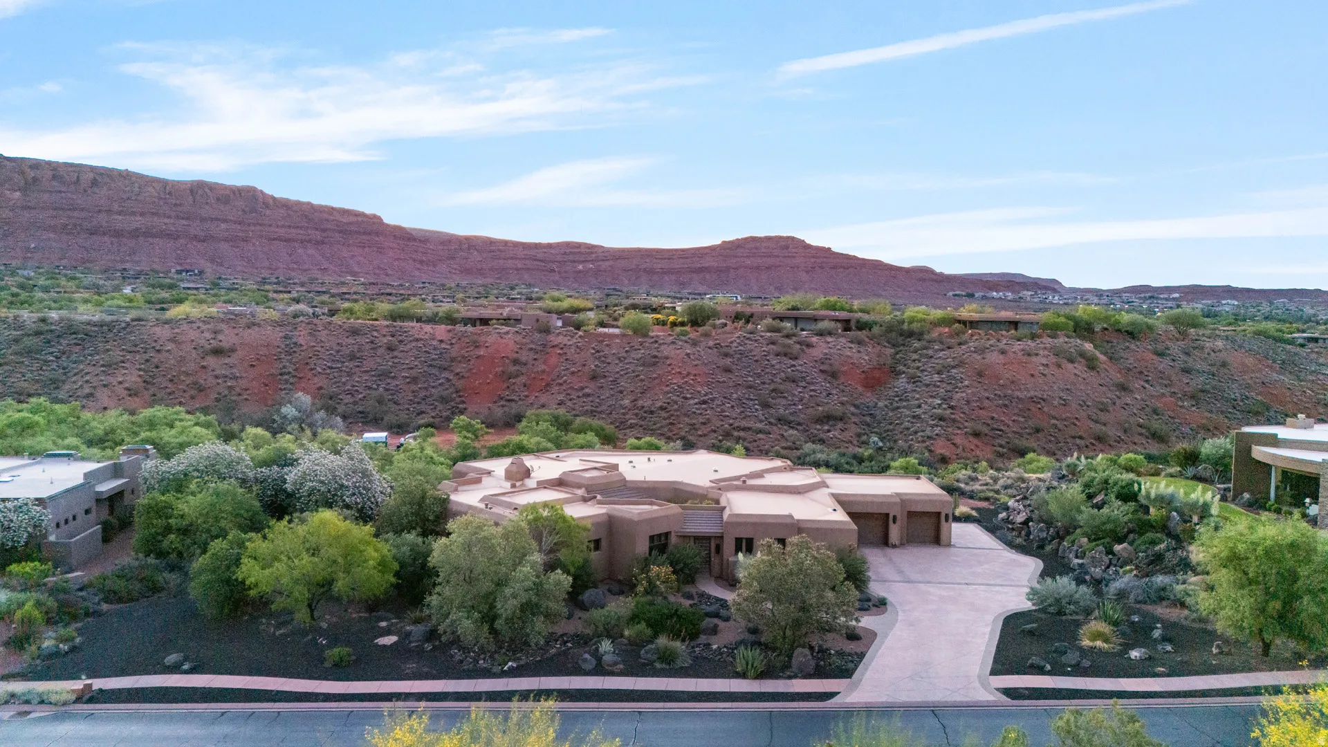Desert contemporary residence featuring a multi-car garage, an expansive driveway, and natural landscaping