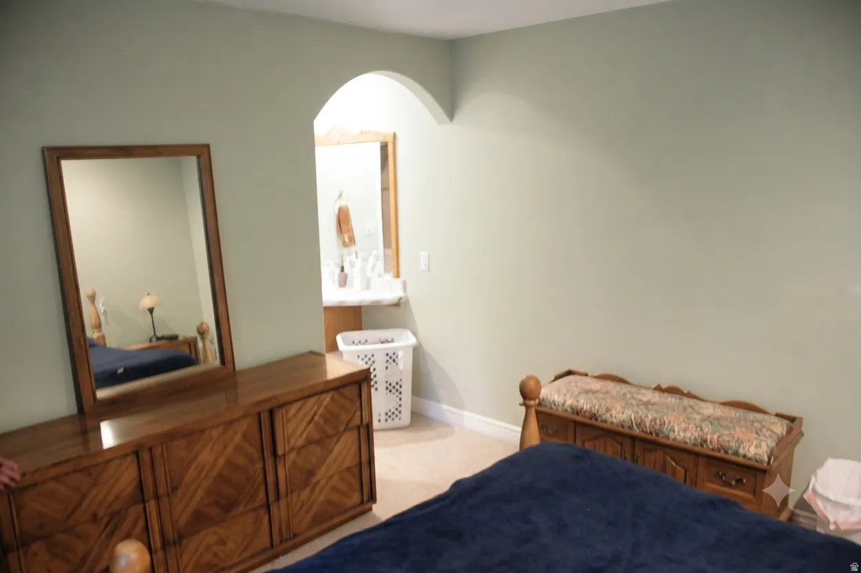 Bedroom featuring neutral wall color and an arched doorway leading to a vanity area