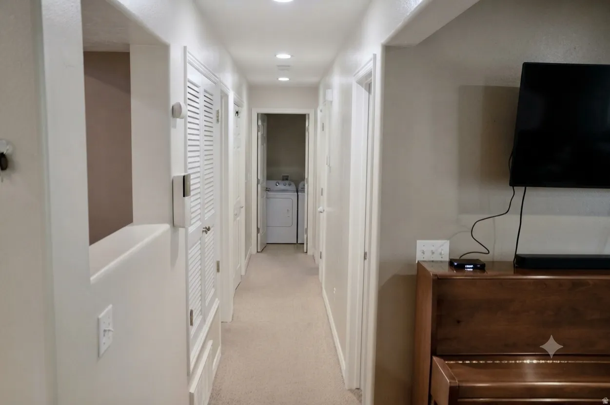 Hallway featuring recessed lighting, a laundry area with white appliances, and a built-in half-wall opening