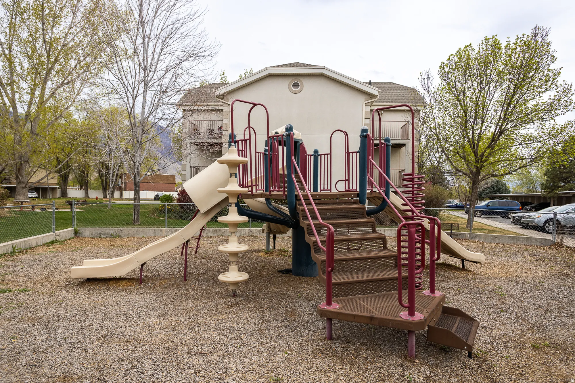 Recreational playground featuring two slides, stairs with handrails, and a spiral ladder