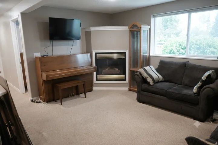 Carpeted living area featuring a built-in fireplace with white trim and a large window