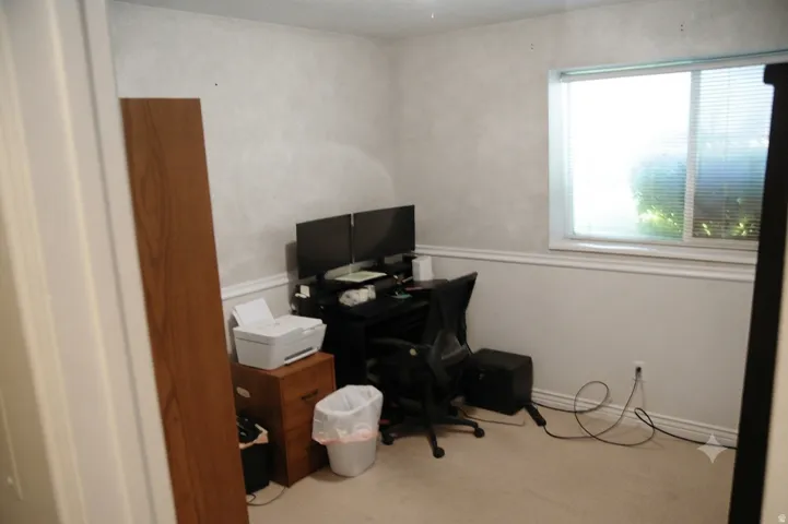Room featuring a single window, light-colored wall-to-wall carpeting, and white baseboards with chair rail molding