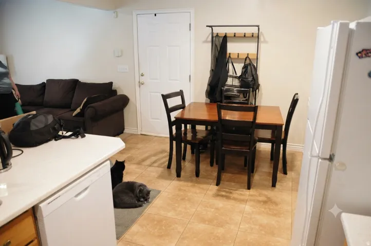 Open-concept living area featuring light-toned tile flooring, white walls, and a white interior door