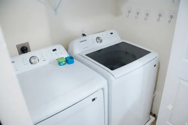 Dedicated laundry area featuring a white top-load washing machine and a white electric dryer