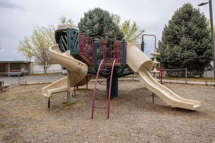 Community playground featuring a multi-level structure with two slides, climbing elements, and a ladder