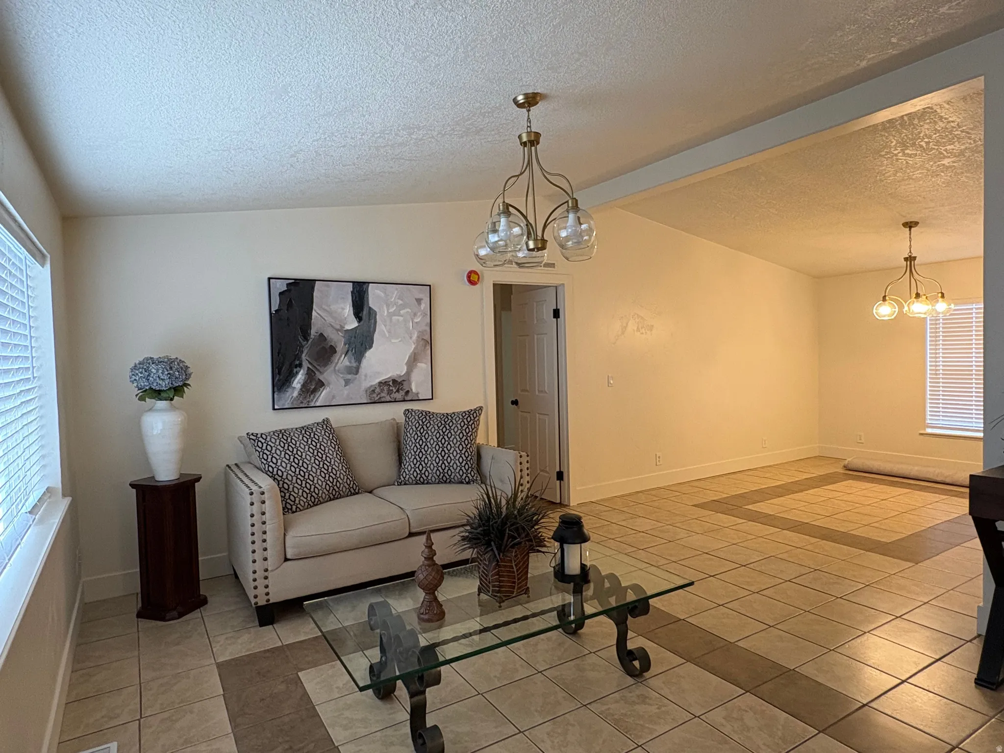 Open-concept living space with tile flooring, a decorative inlaid tile border, and a ceiling-mounted light fixture