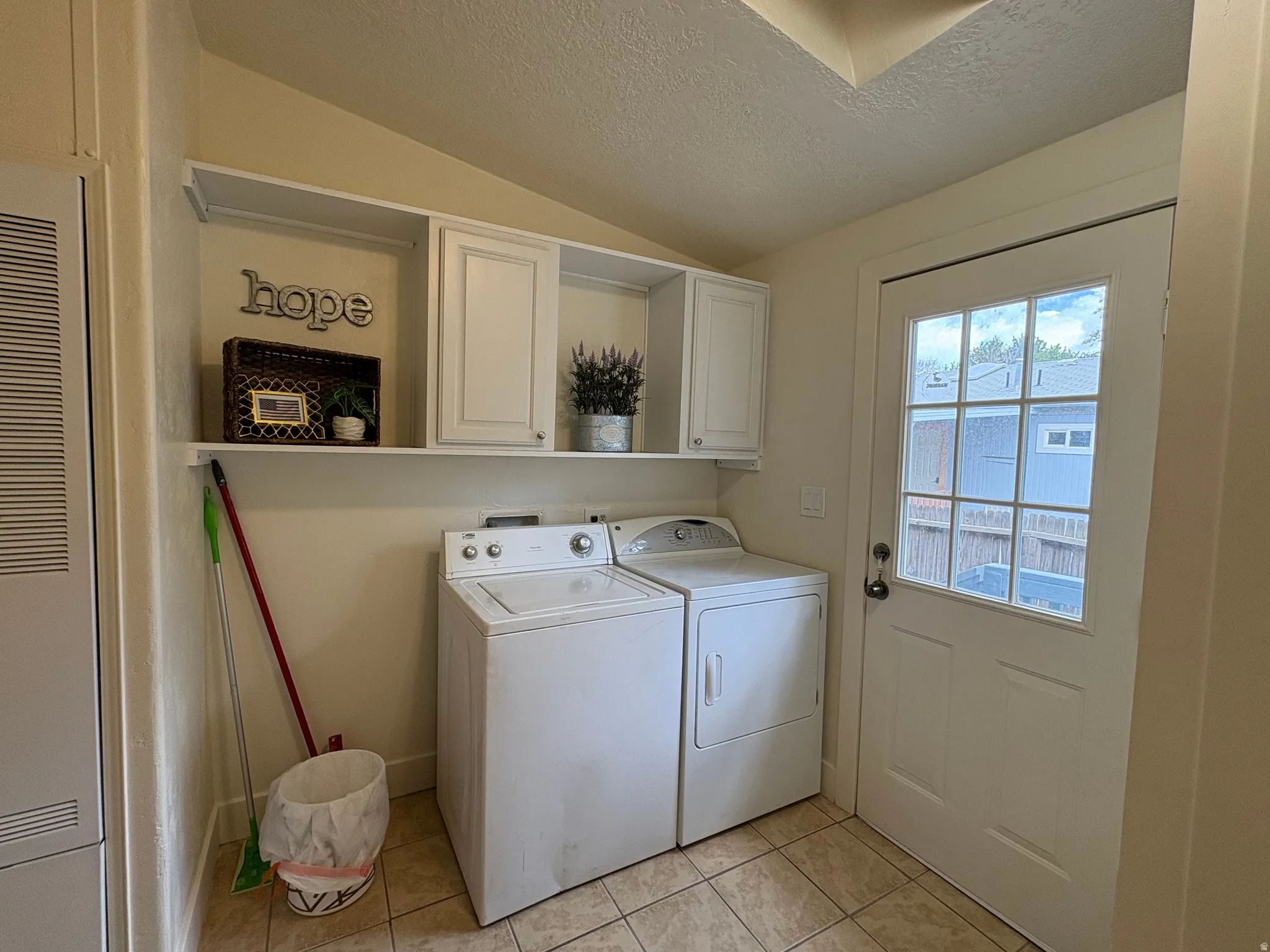 Functional utility space featuring tile flooring, white shaker-style cabinetry, and a glass-paned exterior door