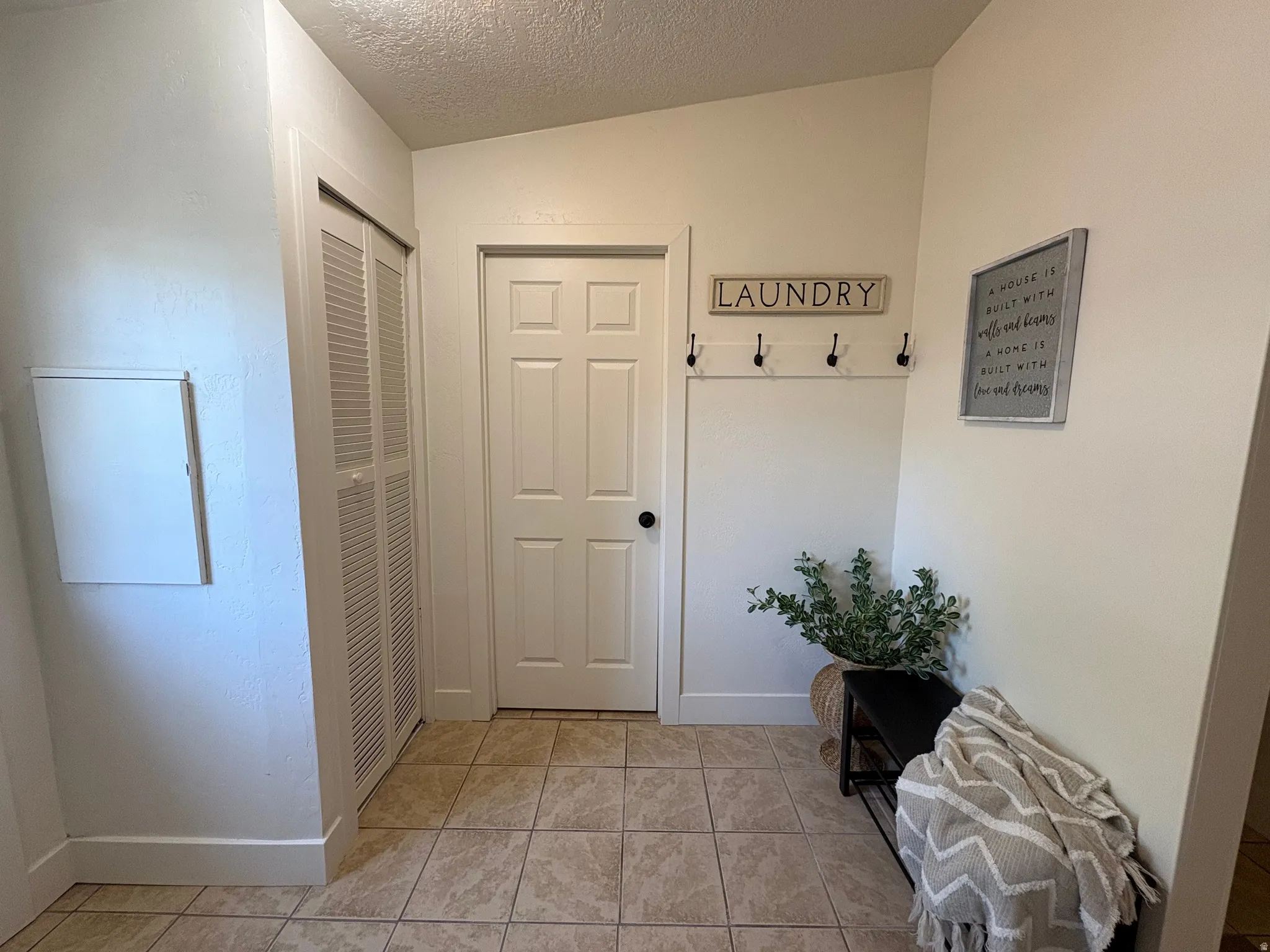 Tiled flooring entry space featuring a six-panel door, bifold louvered closet doors, and white baseboards