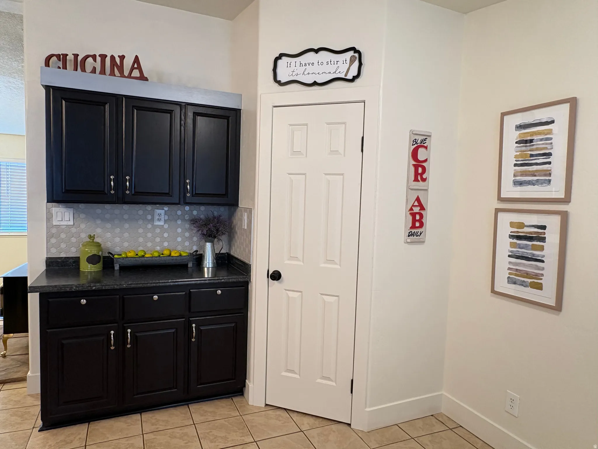 Kitchenette featuring dark-finish cabinetry, a solid surface countertop, and a circular tile backsplash