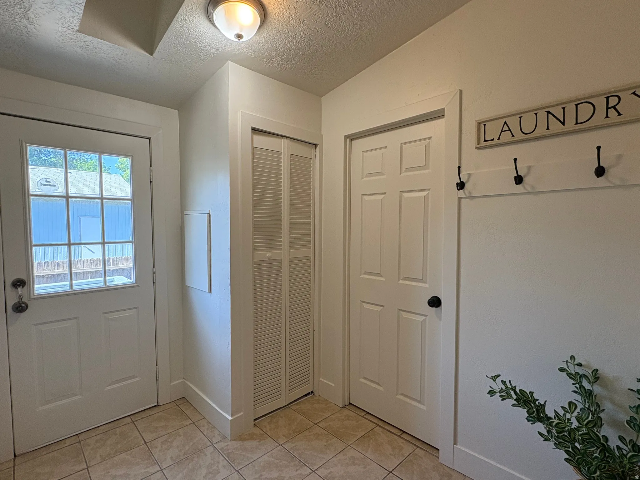 Entryway featuring tile flooring, a white paneled door, louvered bi-fold doors, and a glass-paned exterior door