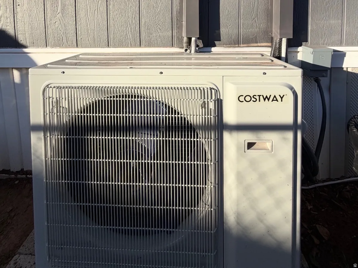 Exterior utility unit featuring a white finish and a prominent fan grille, positioned against vertical panel siding