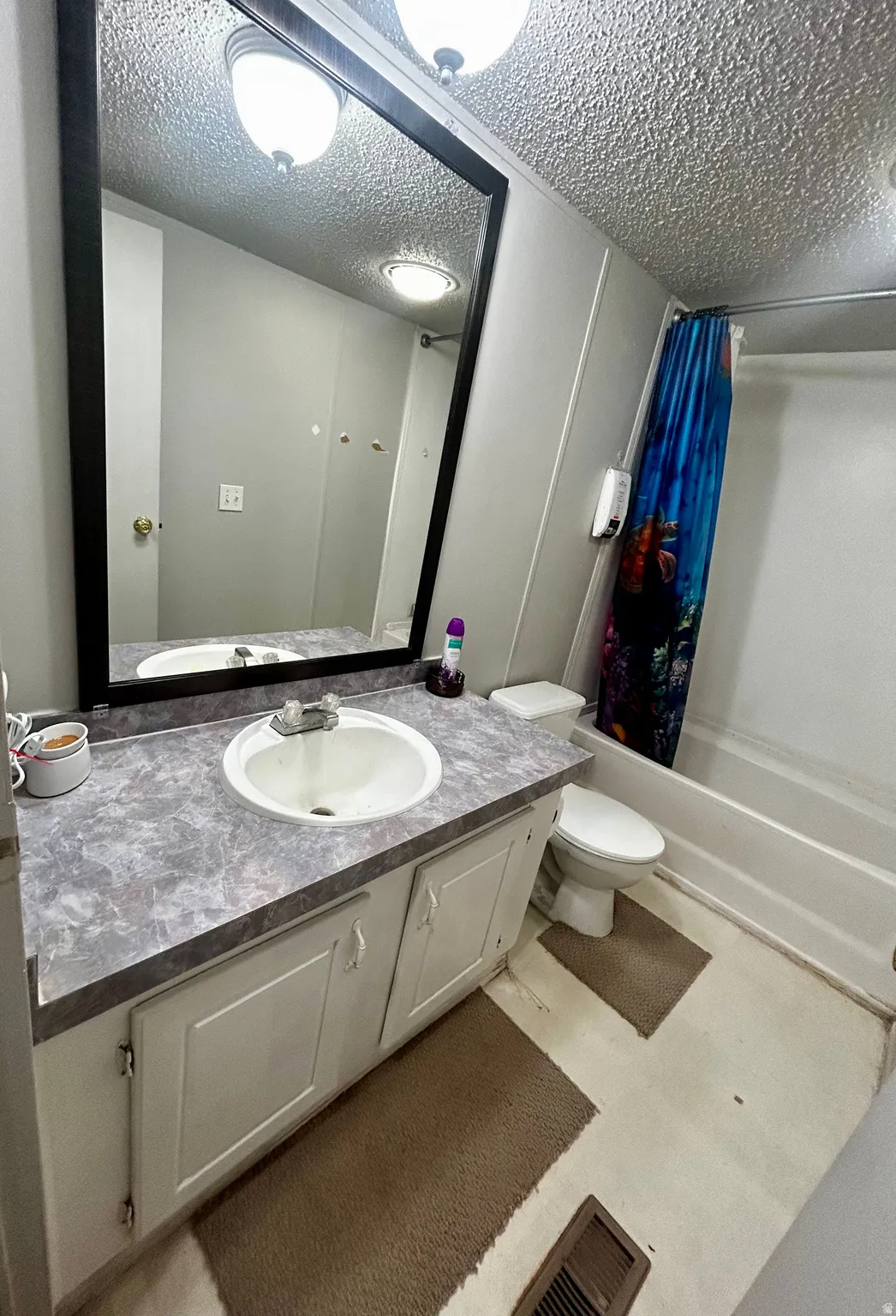 Bathroom featuring a vanity with an integrated sink, a gray patterned countertop, and white cabinetry