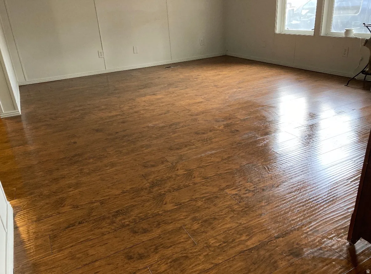 Spacious interior room featuring wood-finish flooring, white baseboards, and bright windows