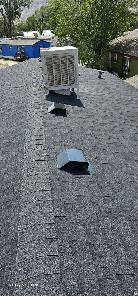 Dark gray asphalt shingle roof featuring a rooftop evaporative cooler unit and multiple roof vents