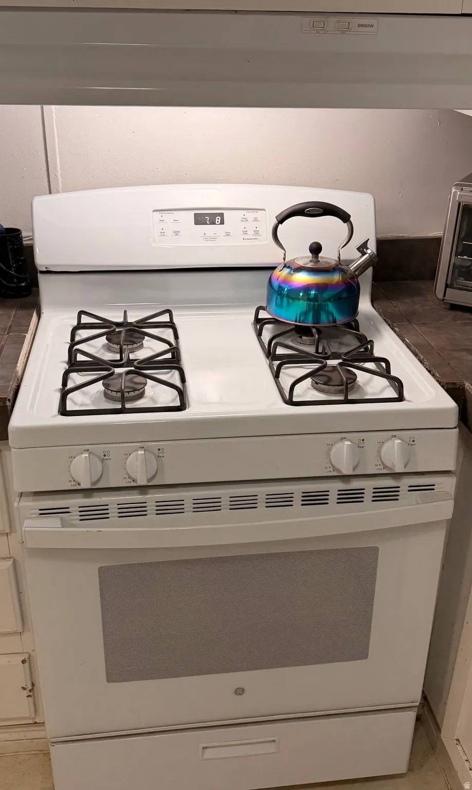 White freestanding range with four gas burners, control panel, and oven below