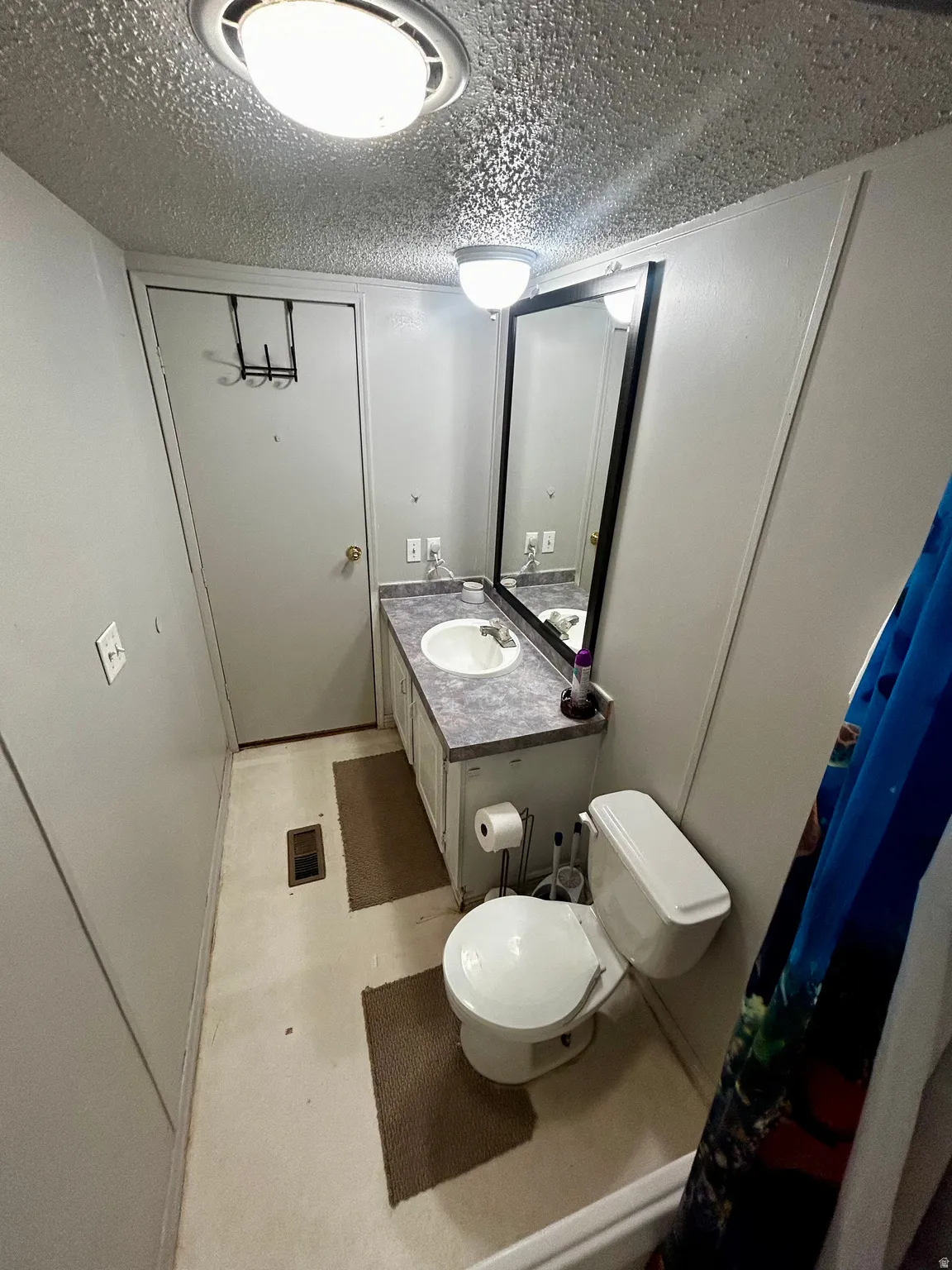 Bathroom featuring a vanity with an integrated sink, a large wall-mounted mirror, and overhead lighting fixtures